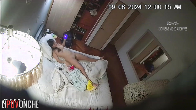 Brunette masturbates to porn in the bedroom on the bed