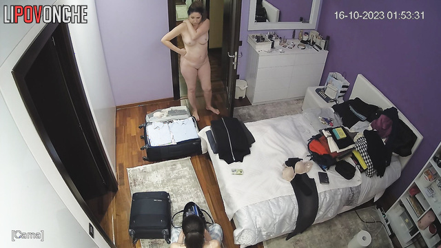 A girl packs a suitcase, and another one walks naked in front of her
