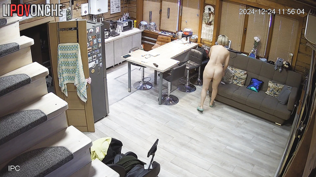 A naked blonde milf slowly gets dressed in the middle of the room while watching TV