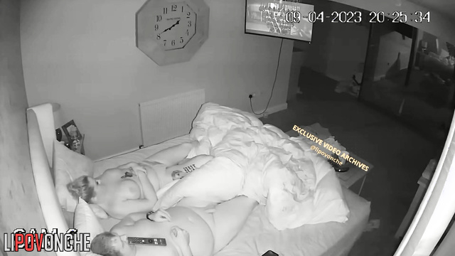 A completely naked chubby man plays on his tablet while his wife sleeps