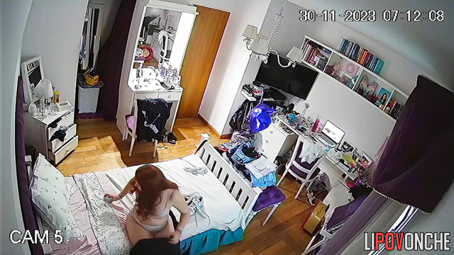 A girl with red hair is looking in the mirror to see how new bra fits on her tits