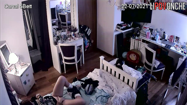 A bored girl gently plays with her labia in her own bed while watching porn