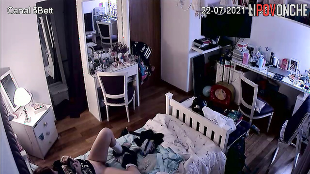 A bored girl gently plays with her labia in her own bed while watching porn