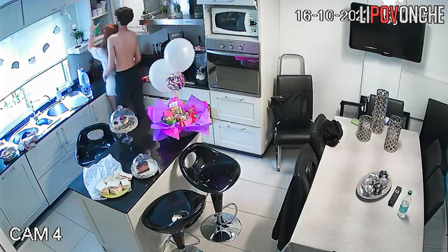 A young guy is making a pass at his redheaded girlfriend right in the kitchen