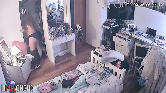A girl with long red hair raises her hands to lift her firm tits in front of the mirror