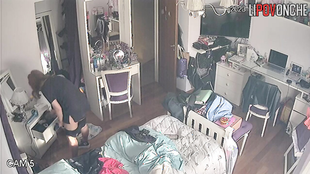 A pretty redheaded girl is walking around the bedroom with her panties down