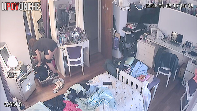 A pretty redheaded girl is walking around the bedroom with her panties down