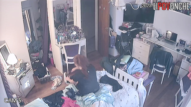 A pretty redheaded girl is walking around the bedroom with her panties down