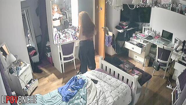 The redheaded girl undresses and gazes with interest at her firm tits in the mirror