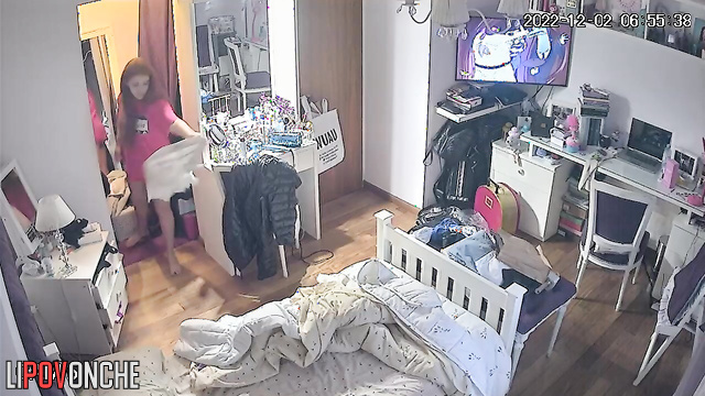 A red-haired cutie is watching TV, stripped down to her panties with her tits exposed