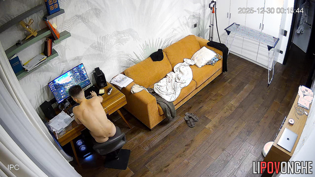 A girl with small breasts smiles at her naked husband, who is sitting at the computer