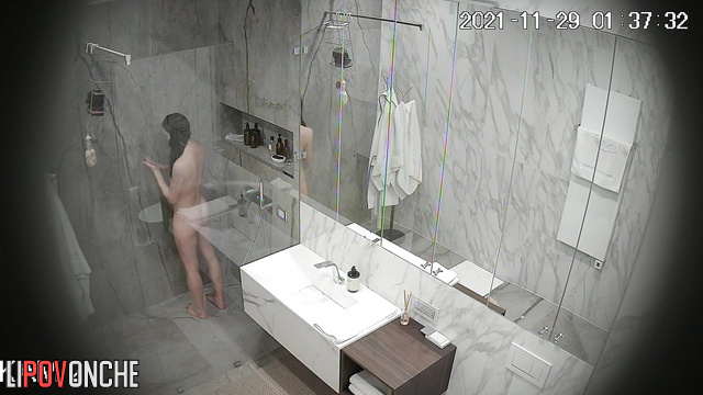 An sporty girl directs the warm stream of water from the shower onto her hairy pussy