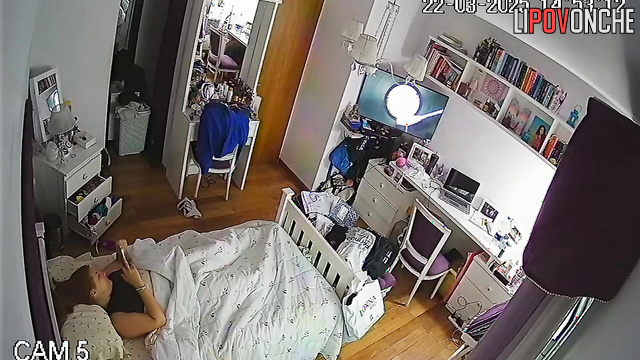 A bored redhead secretly masturbates under the covers while watching porn