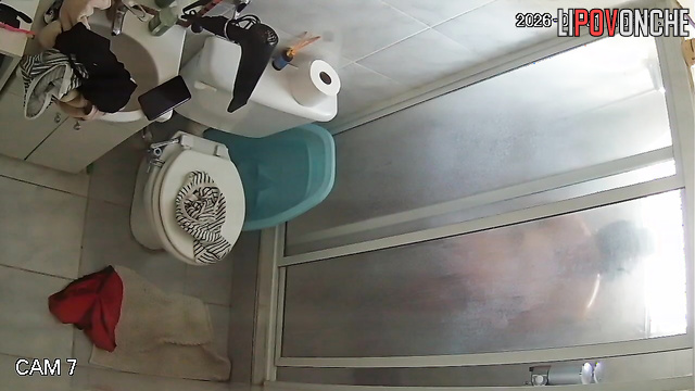 A pregnant brunette undresses before taking a shower while sitting on the toilet