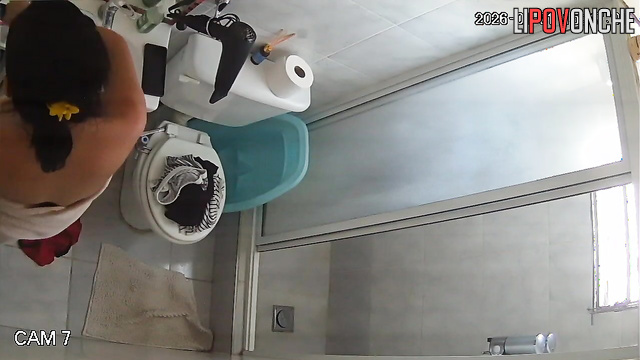 A pregnant brunette undresses before taking a shower while sitting on the toilet