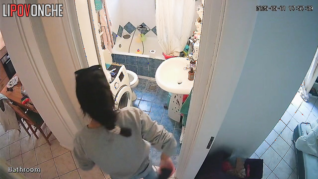 A girl with her panties down is sitting on the toilet with her naked butt