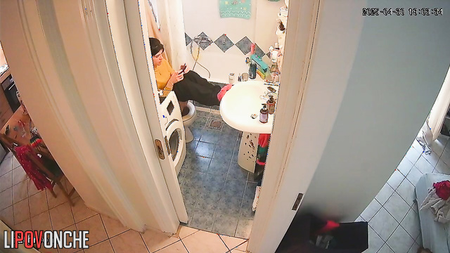 A young cutie has her legs up on the sink, sitting on the toilet with her bare ass