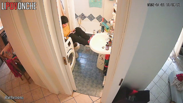 A young cutie has her legs up on the sink, sitting on the toilet with her bare ass