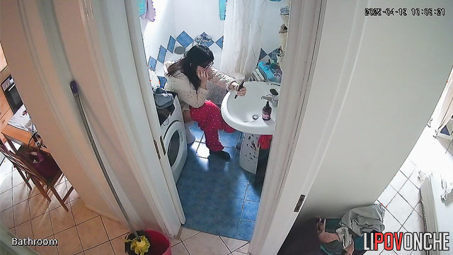A housewife, sitting right on the toilet, spends a long time washing her butt