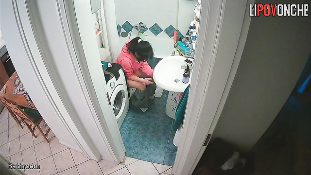 A girl, sitting on the toilet without panties, lifts her sexy legs high