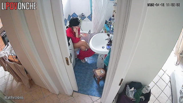 A beauty examines her shaved pussy while sitting on the toilet without panties