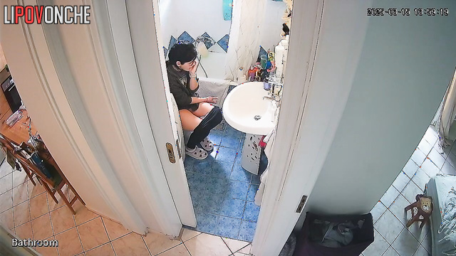 A housewife is talking on the phone while sitting on the toilet with naked ass