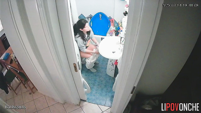 After washing her hands, a delightful cutie pulls down her panties to pee