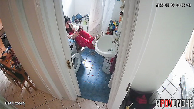 A brunette, sitting on the toilet, lifts her legs high, exposing her bare bottom