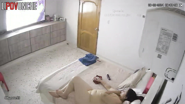 A sexy, chubby brunette, completely naked, is bored in bed while watching TV