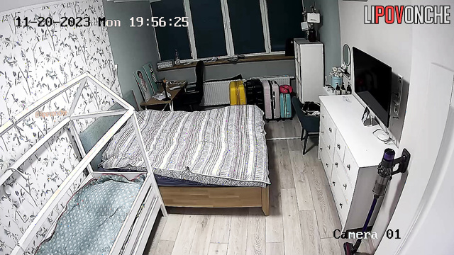 A completely naked woman with large breasts is making the bed in the bedroom