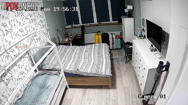 A completely naked woman with large breasts is making the bed in the bedroom