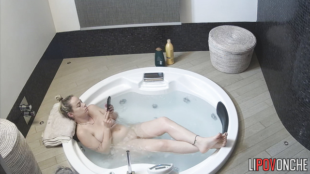 Pretty blonde lying in a jacuzzi and texting her friend
