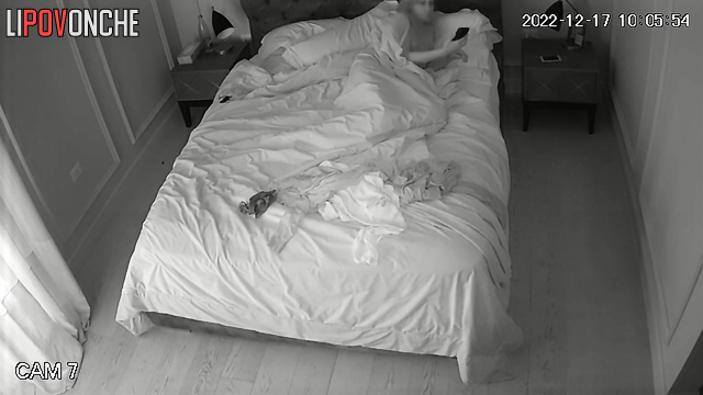 Awake beauty with bare breasts is bored in bed, looking at her phone