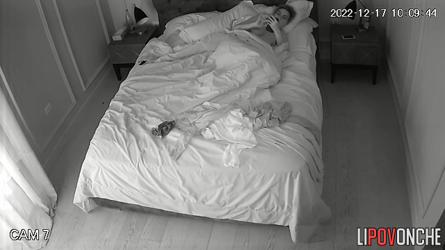 Awake beauty with bare breasts is bored in bed, looking at her phone