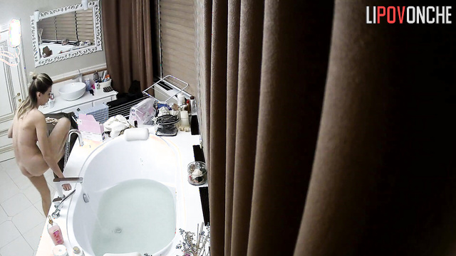 A slim girl with a pumped ass wets her shaved pussy before taking a bath