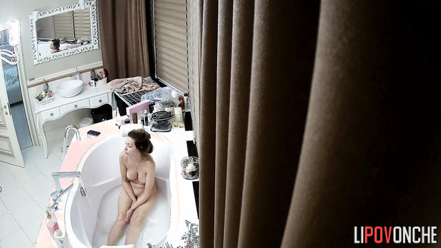 A seductive, slender cutie, completely naked, is bored in the bathtub with her phone