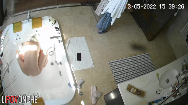 An older teacher with big tits washes her shaved pussy in the bathtub