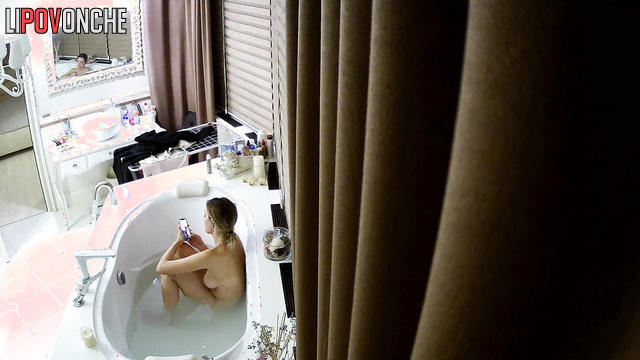 Blonde likes to text while sitting in the bath, look