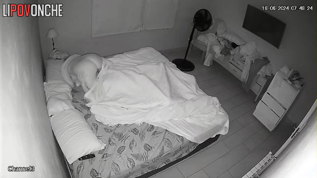 An unshaven man arouses his sleepy wife by playing with her nipples with his tongue