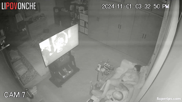 An elderly bald man plays with a voluptuous milf's wet pussy while watching TV